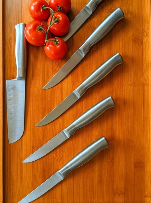 wooden chopping board, tomatoes, silver knives