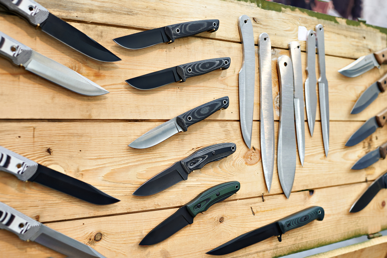 Hunting and tactical knives on wooden stand in store